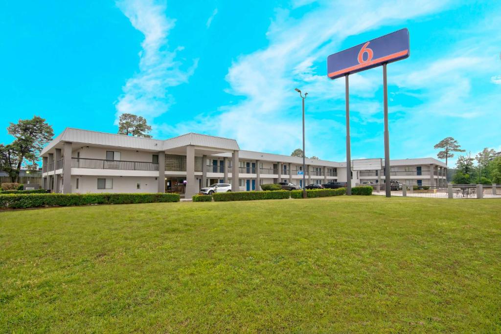 un edificio con un cartello di fronte a un campo di Motel 6 Texarkana, TX a Texarkana