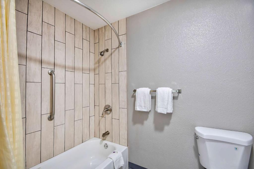 a bathroom with a toilet and a shower with towels at Motel 6 Texarkana, TX in Texarkana