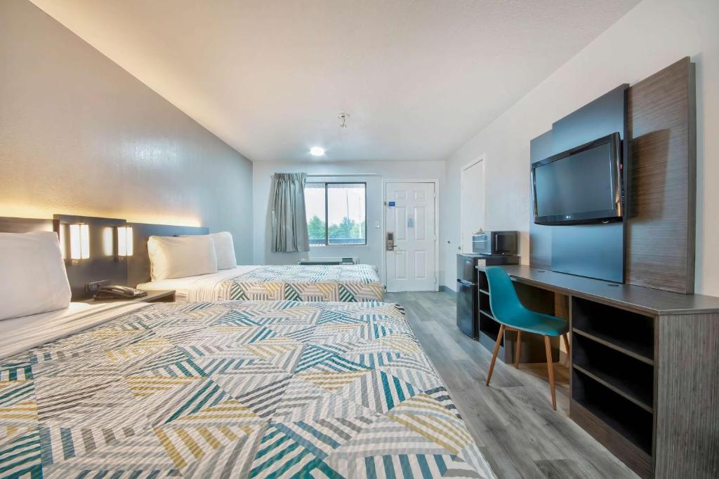 a hotel room with two beds and a desk and a television at Motel 6 Texarkana, TX in Texarkana