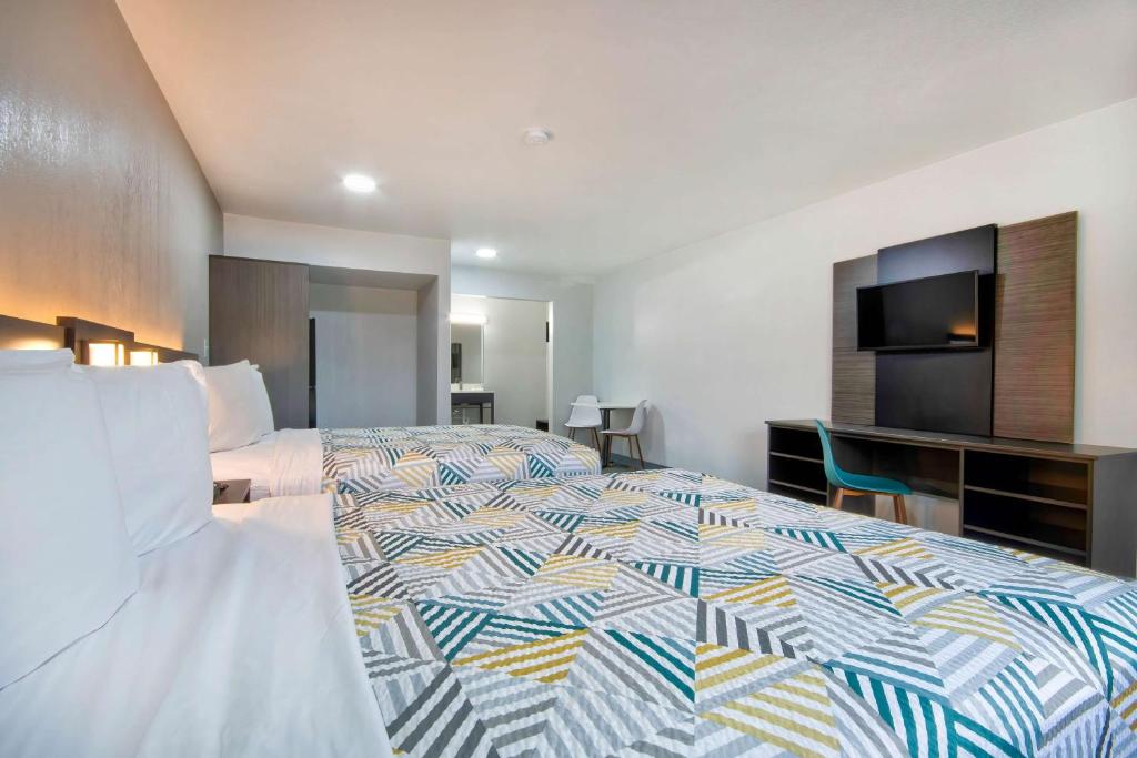 a hotel room with a large bed and a television at Motel 6 Texarkana, TX in Texarkana