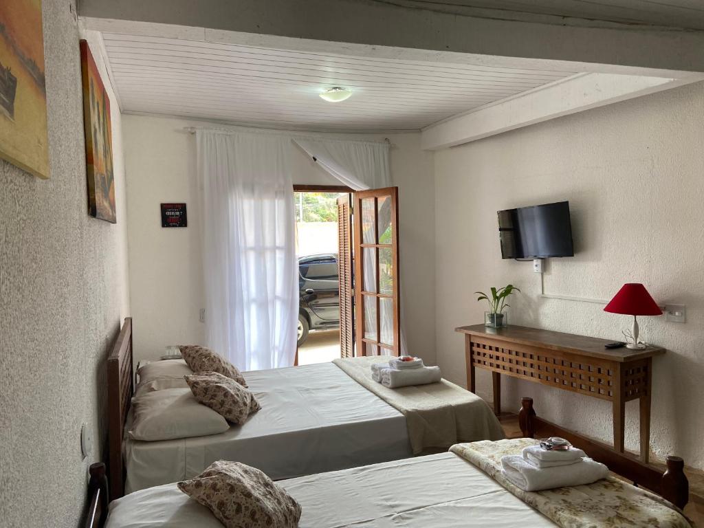 a bedroom with two beds and a tv on the wall at Pousada Maresias de Geribá in Búzios