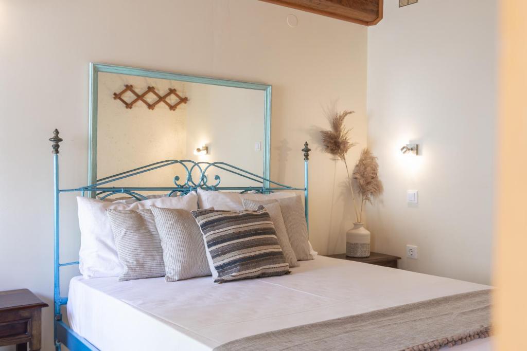 Schlafzimmer mit einem Bett mit weißer Bettwäsche und Kissen in der Unterkunft Villa Theodora View Apartments Thalia in Agios Georgios Pagon