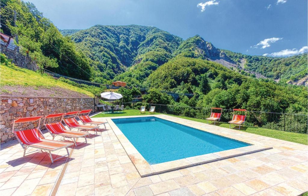 uma piscina com cadeiras e montanhas ao fundo em Il Daino em Sassalbo