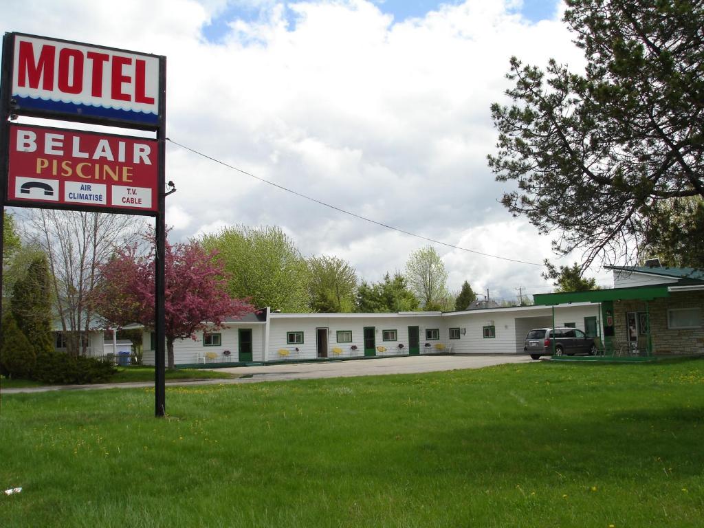um sinal de motel na relva em frente a um edifício em Motel Belair em Rigaud