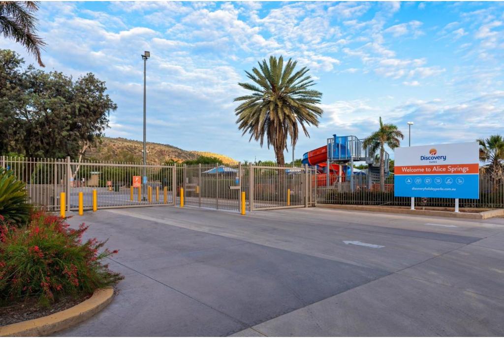 un estacionamiento con una valla y una señal en Discovery Parks - Alice Springs, en Alice Springs