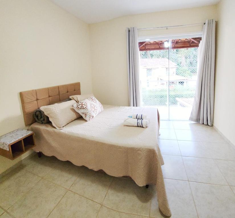 a bedroom with a bed and a large window at casa da cris in Miguel Pereira