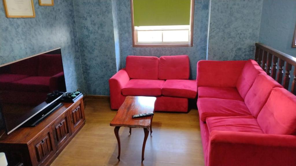 a living room with a red couch and a table at Habitación 1 casa/tinaja/piscina in Valdivia