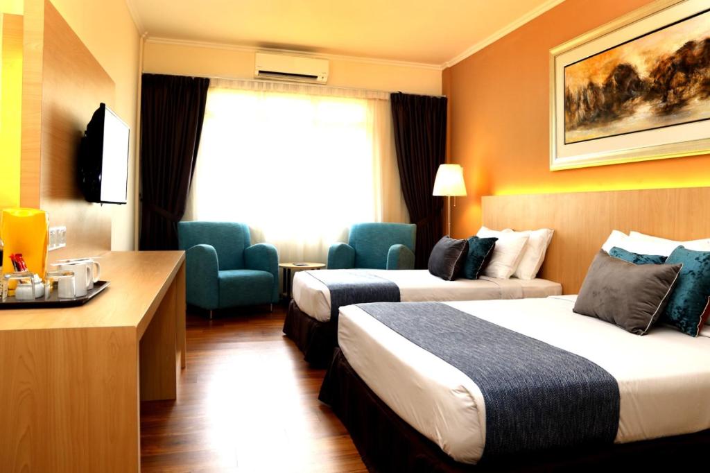 a hotel room with two beds and a desk at Hotel Seri Malaysia Seremban in Seremban