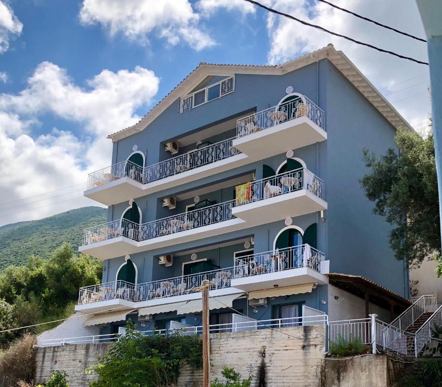 niebieski budynek z balkonami na wzgórzu w obiekcie Seaview Rooms w mieście Vasiliki