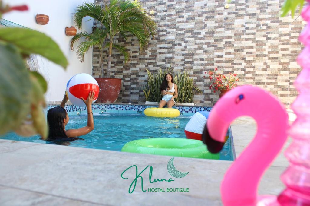 two women playing with a ball in a swimming pool at K Luna Hostal Boutique in Ríohacha