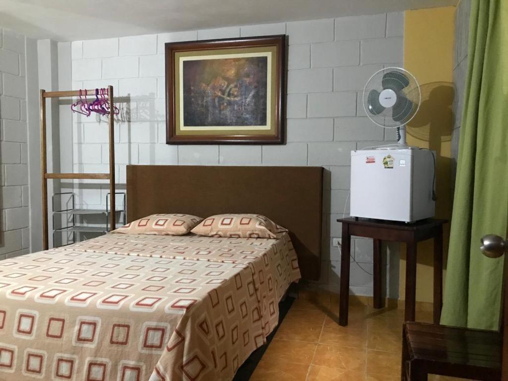 1 dormitorio con 1 cama y nevera. en Linda habitación de hotel en Trujillo, en Palomar