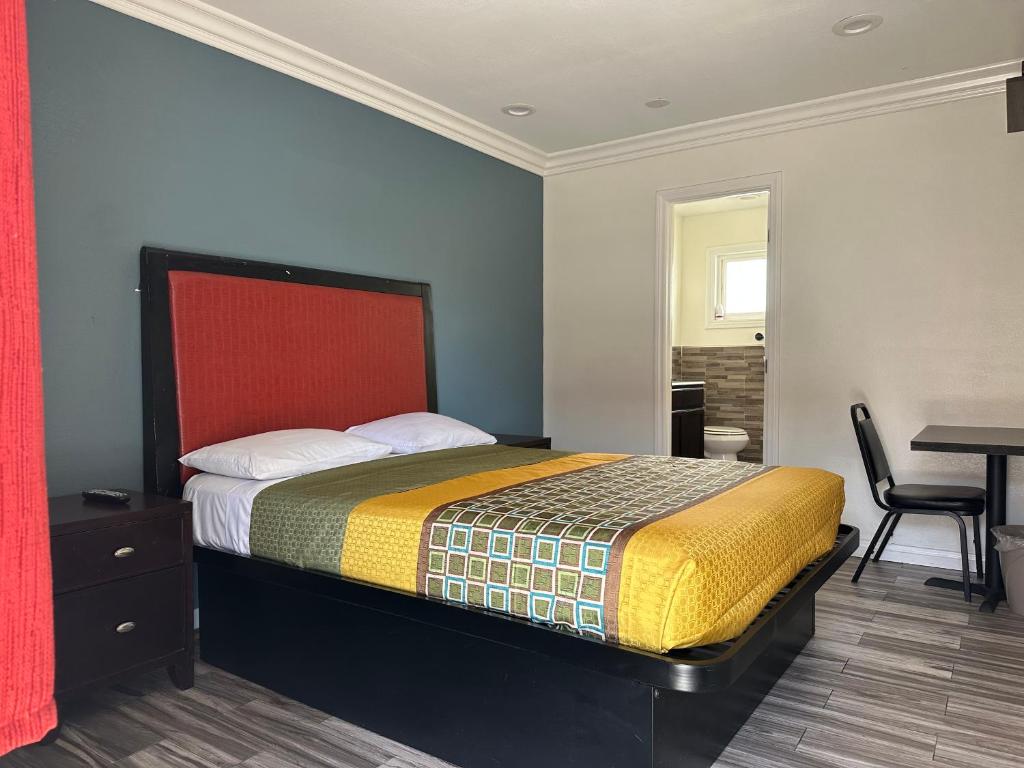 a bedroom with a bed with a red headboard and a table at Bartlett Motel in Lomita