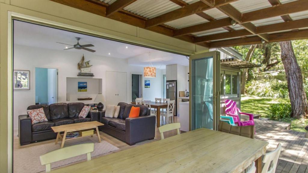 a living room with a table and a couch at Coastal Chic Holiday Cottage in Pearl Beach