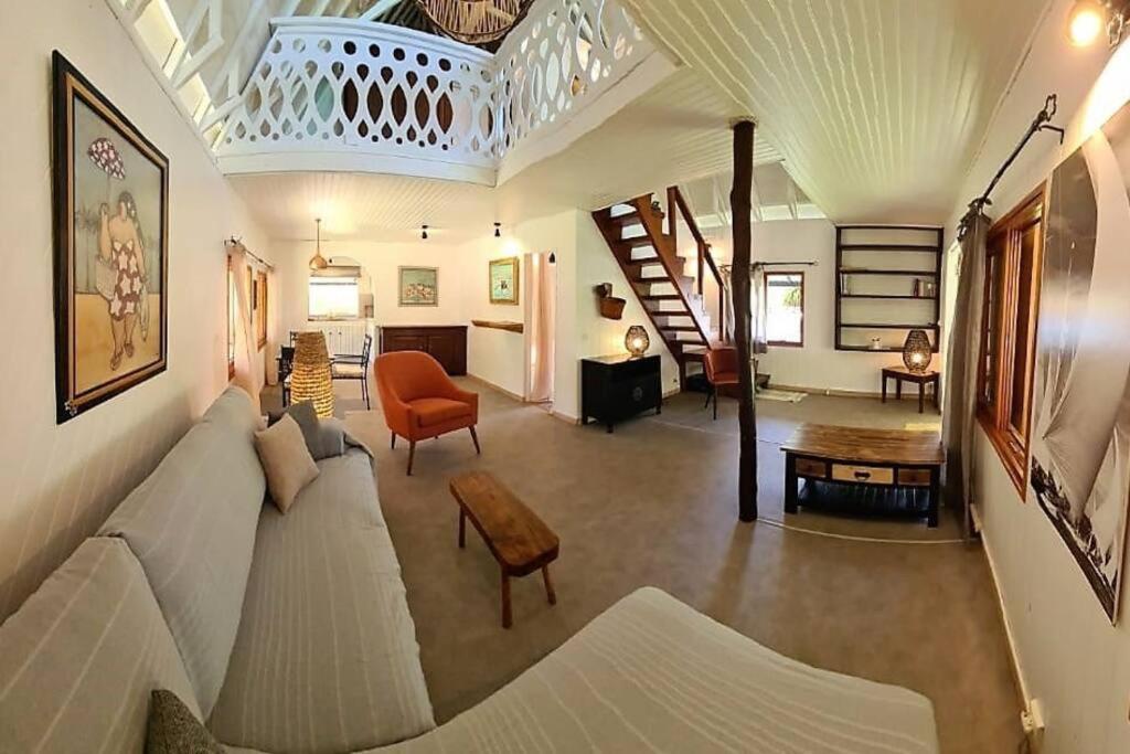 a living room with a couch and a table and a staircase at Green Villa Moorea in Temae