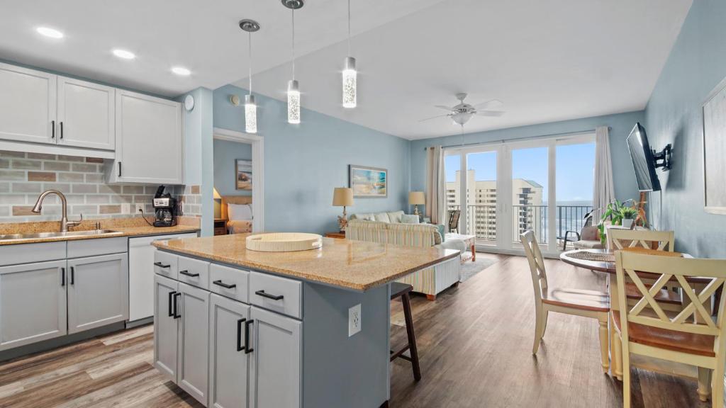a kitchen with blue walls and a dining room with a table at Some Beach Some Where at Laketown Wharf #825 by Nautical Properties in Panama City Beach