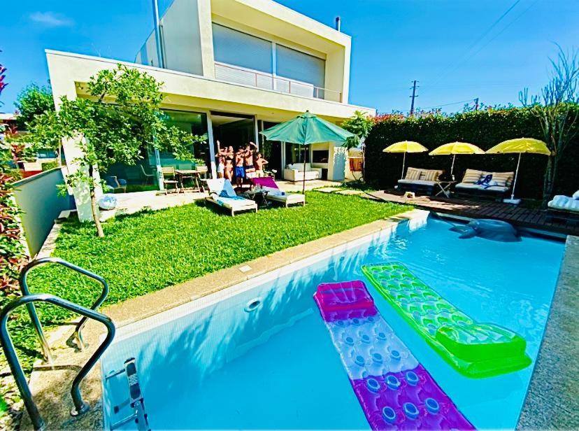 uma piscina com cadeiras e guarda-sóis ao lado de uma casa em Portugal Holidays Villa - HOUSE CAR FOR GUEST USE INCLUDED IN THE DAILY RATE em Barcelos