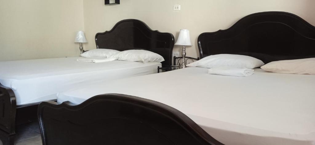 two beds with black headboards in a room at Residencial derosas 