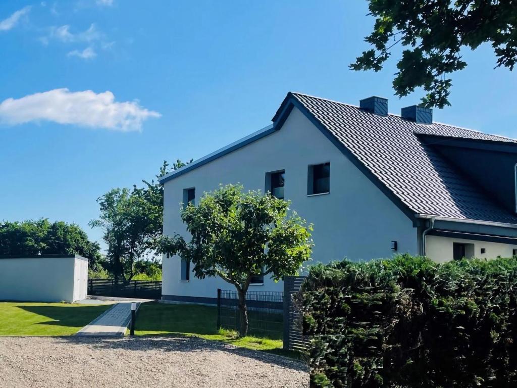 una casa bianca con un albero davanti di Cosy holiday home HELMA directly at the Baltic Sea a Zierow