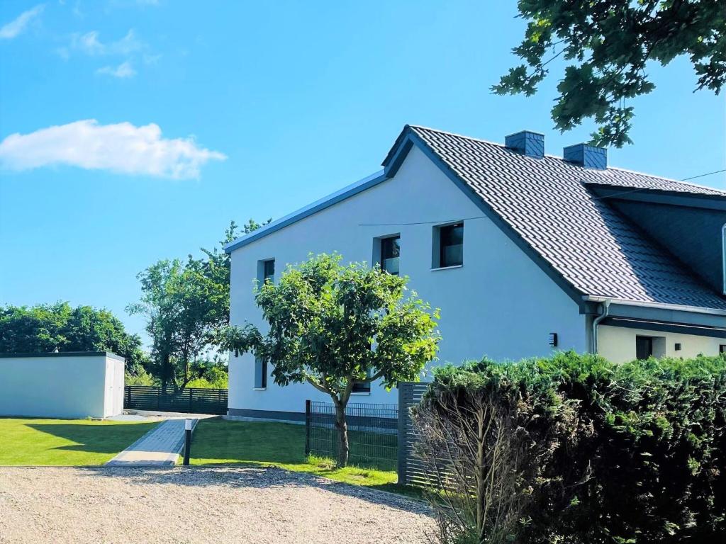 Una casa blanca con un árbol delante. en WILMA holiday home directly at the Baltic Sea, en Zierow
