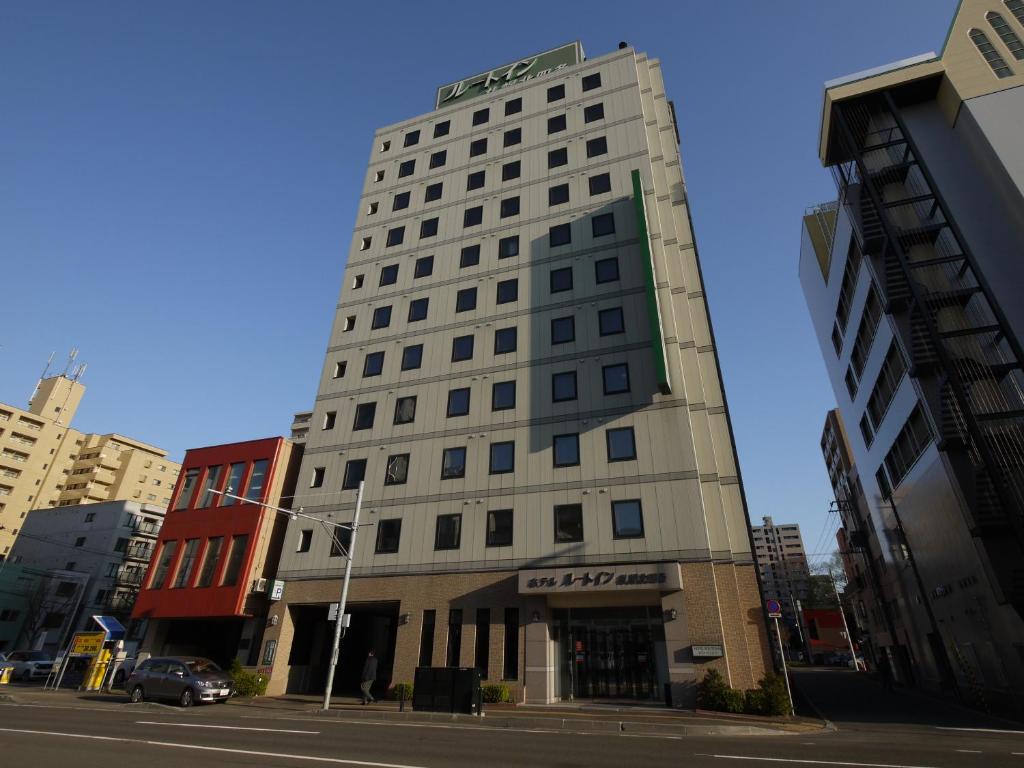 een hoog wit gebouw in een stadsstraat bij Hotel Route-Inn Sapporo Kitayojo in Sapporo