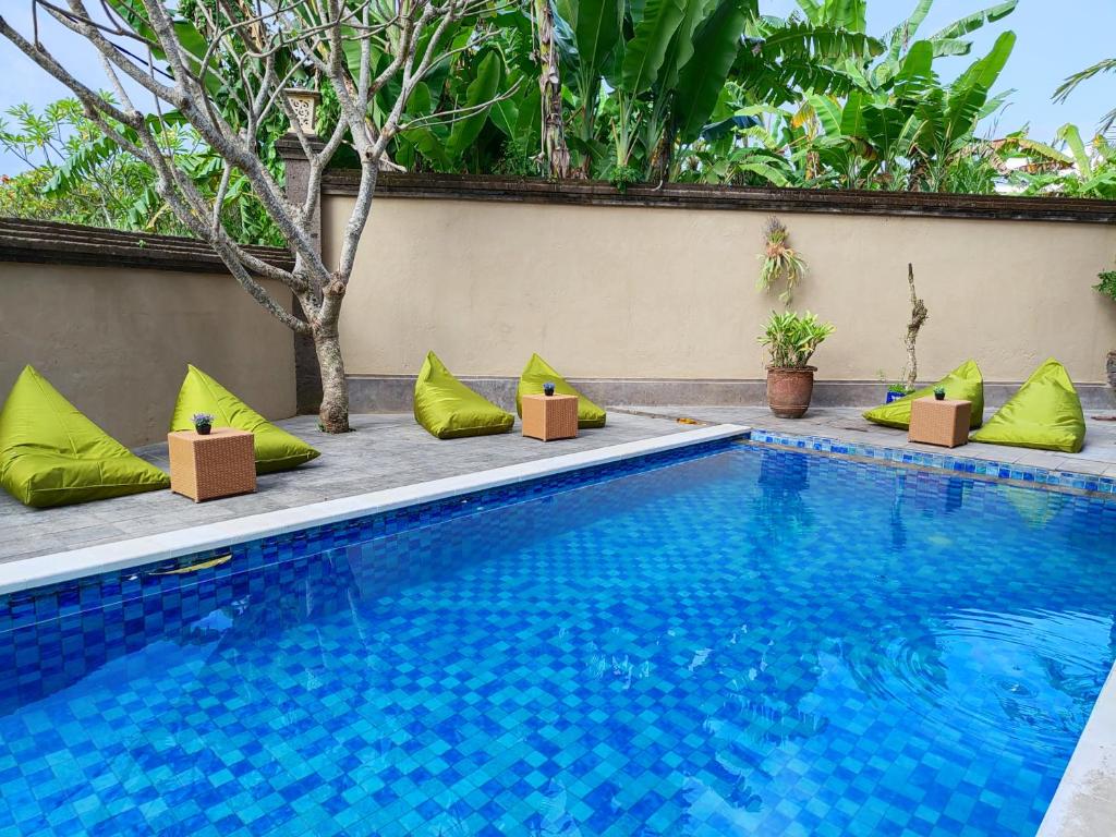 a swimming pool with green pillows next to a building at Starloka Saba Bali Hotel in Blahbatu