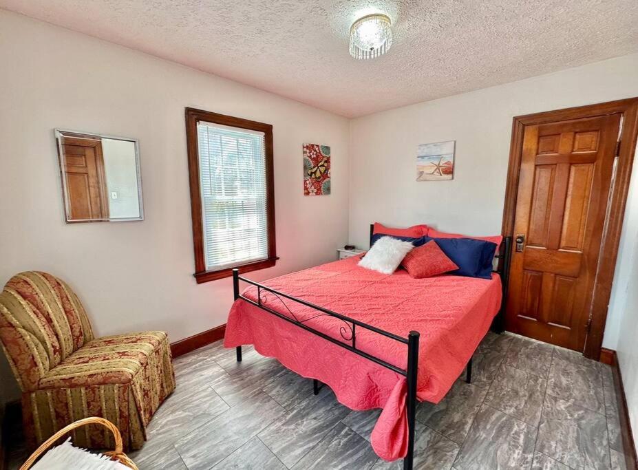 a bedroom with a red bed and a chair at Trestle Creeks Original Farmhouse in Bloomington