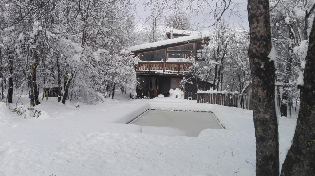Cabaña Lodge los Coihues VALLE LAS TRANCAS# TERMAS DE CHILLAN#NEVADOS DE CHILLAN في Pinto: منزل مغطى بالثلج أمام مبنى