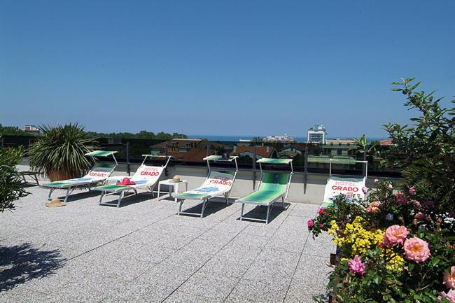 una fila de sillas sentadas en un patio con flores en Hotel Grado, en Bellaria-Igea Marina
