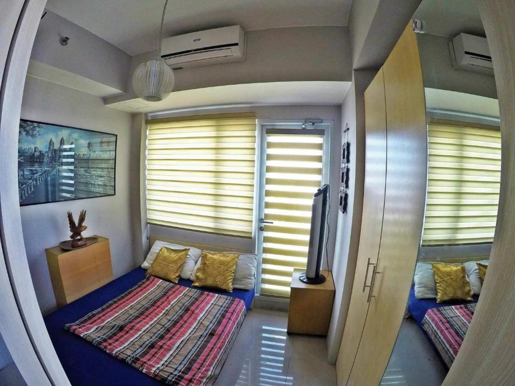 a small room with two beds and windows with blinds at Chill Staycation at Grass Residences in Manila
