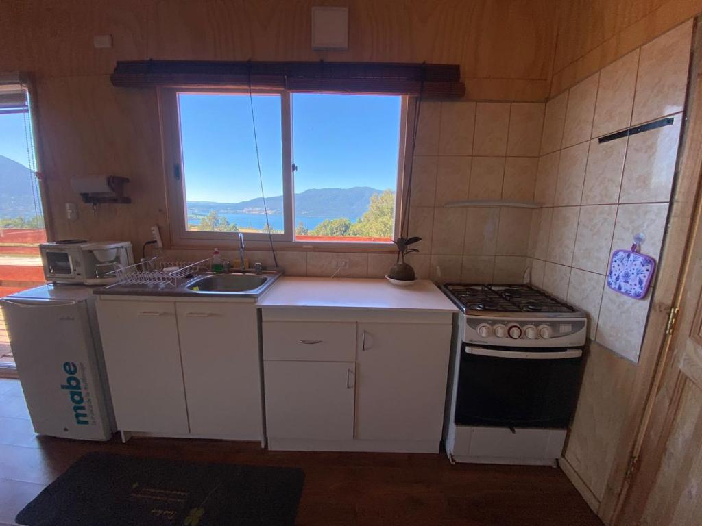 eine Küche mit einem Herd, einem Waschbecken und einem Fenster in der Unterkunft Lomas de Riñihue para 2p in Valdivia