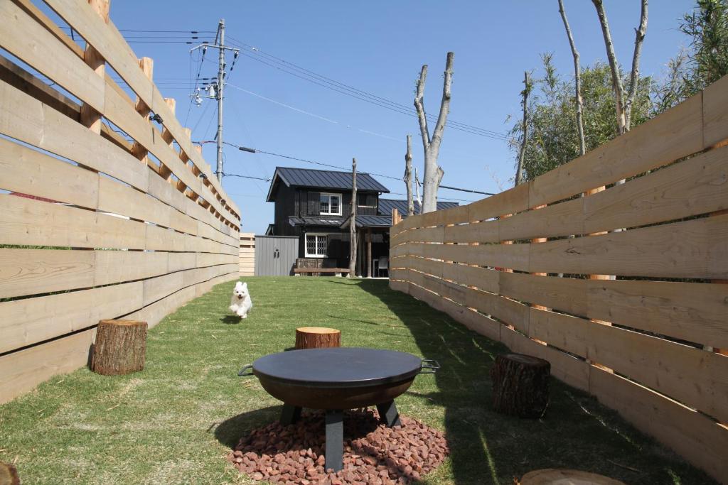 un cane seduto nel cortile di una casa con una recinzione di 愛犬と泊まれるドッグラン付きアンティークハウス-AKIYA cornerstone- ad Awaji
