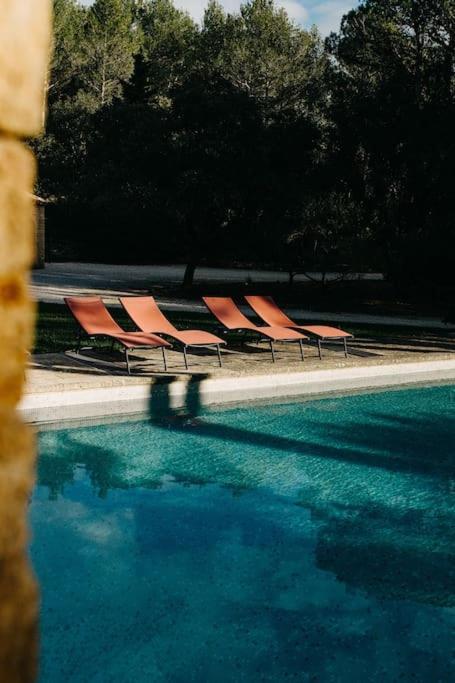 un groupe de chaises assises à côté d'une piscine dans l'établissement Villa des Baumes, à Cornillon-Confoux