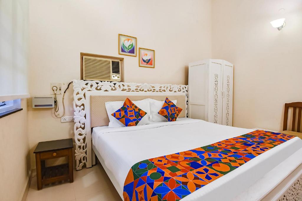 a bedroom with a white bed with a colorful blanket at FabHotel Prime Pool Point Highland, Candolim Beach in Candolim