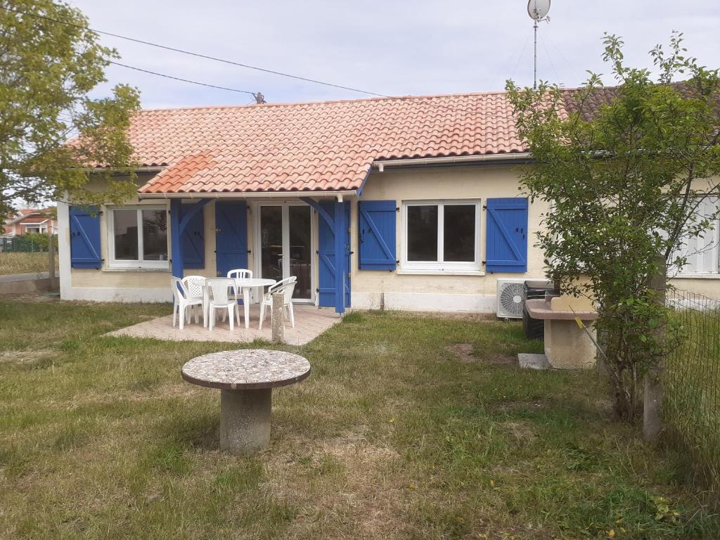 una casa azul con una mesa y sillas en el patio en Cantalaoude en Soulac-sur-Mer