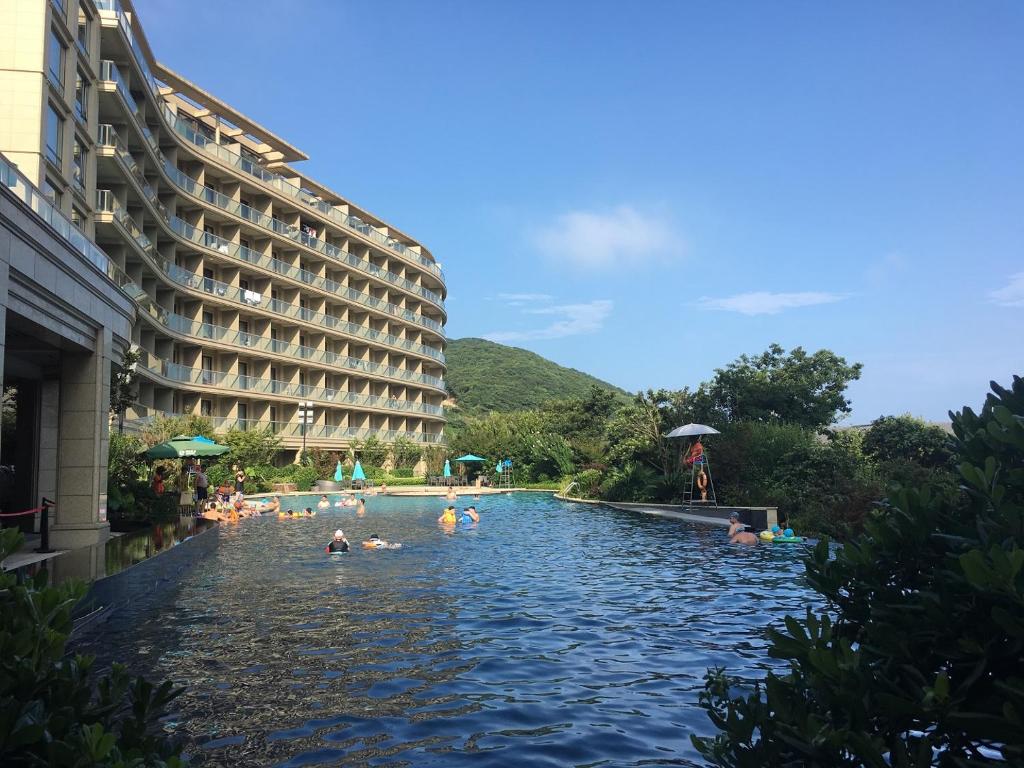 una piscina in un hotel con persone che ci nuotano di 舟山朱家尖东沙绿城品霞苑酒店式公寓 a Zhoushan
