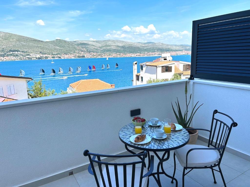 een tafel en stoelen op een balkon met uitzicht op het water bij Apartment One in Okrug Donji