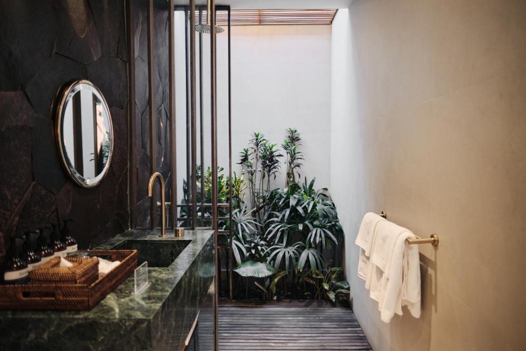 baño con lavabo, espejo y plantas en Munno Villa en Canggu