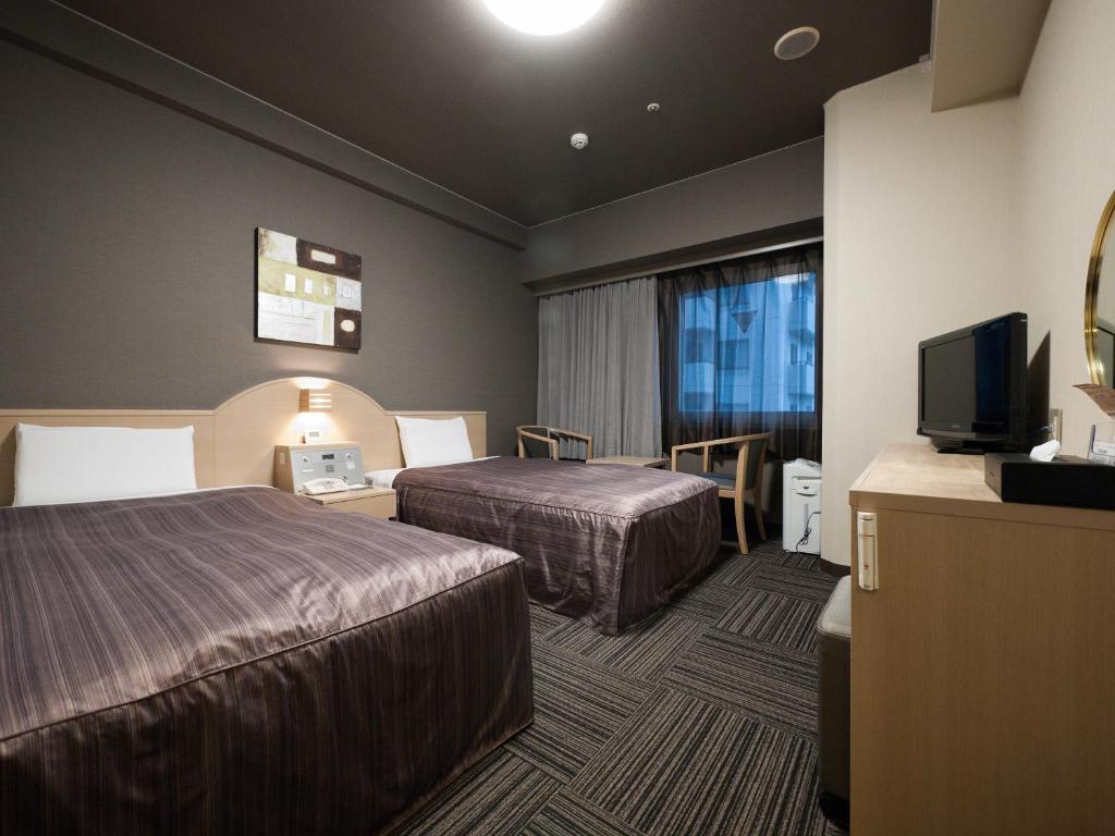 um quarto de hotel com duas camas e uma televisão em Hotel Route-Inn Tokyo Asagaya em Tóquio