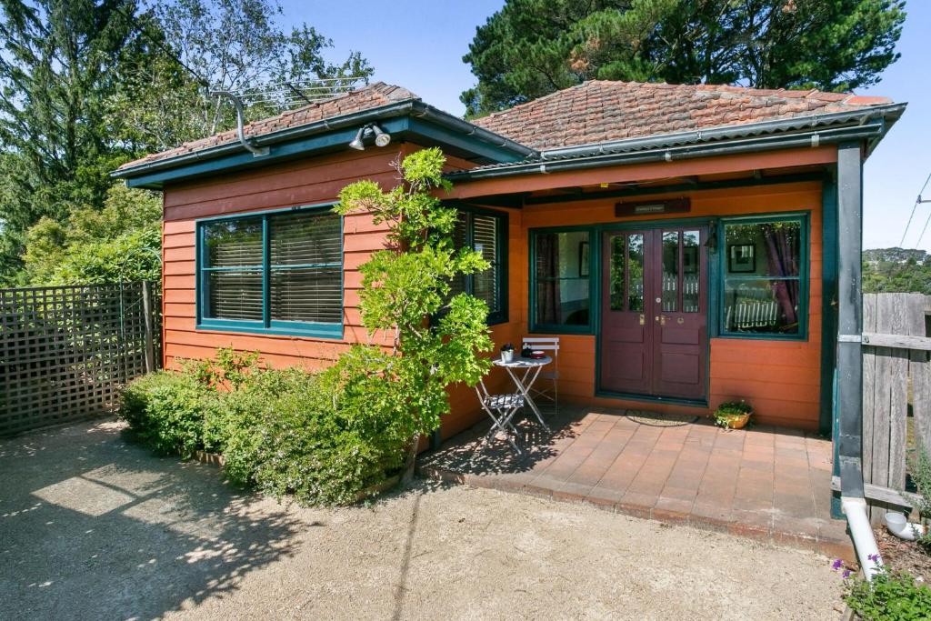 ein kleines orangenes Haus mit lila Tür in der Unterkunft Carinya Cottage in Katoomba