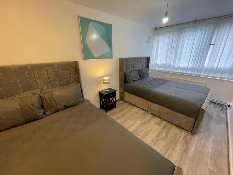 a bedroom with two beds and a couch and a window at Xtra large 2 bedroom LondonFlat in Woolwich