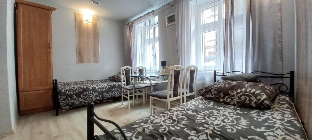 a bedroom with a bed and a table and windows at Hostel CION in Gliwice