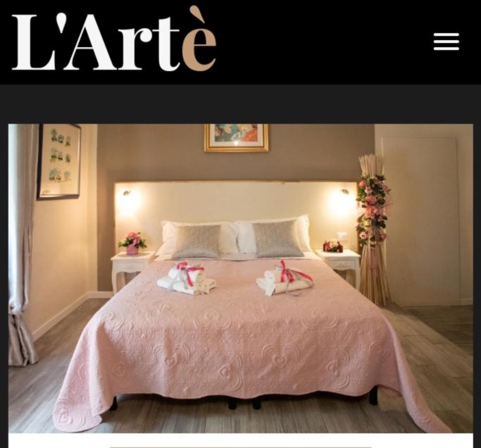 Zwei Puppen sitzen auf einem rosa Bett in der Unterkunft L'artè in Cascina