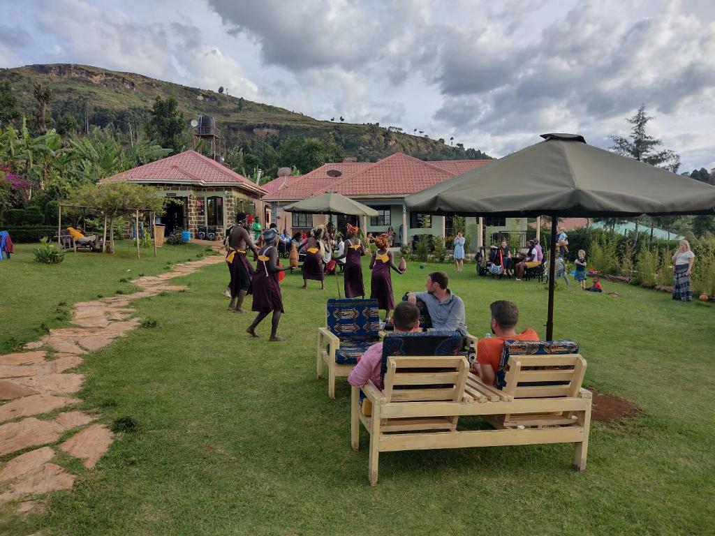 um grupo de pessoas sentadas em cadeiras sob um guarda-chuva em Home of Friends em Kapchorwa