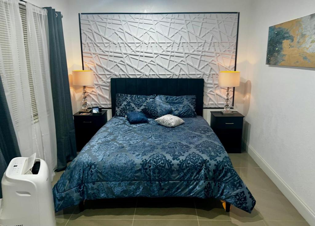 a bedroom with a bed with a blue comforter and two lamps at Miami Gardens Comfort Suite by Hard Rock Stadium in Miami Gardens