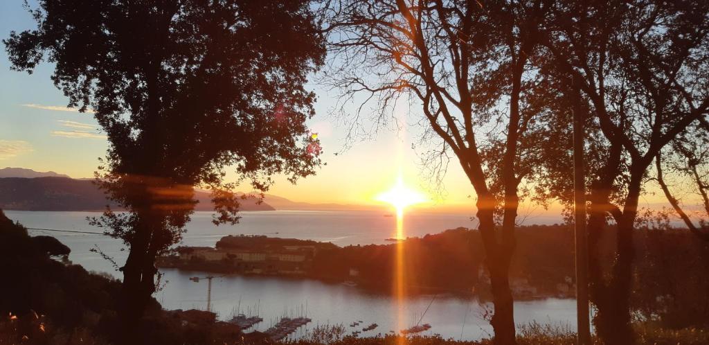 einen Sonnenuntergang über einem Wasserkörper mit Bäumen in der Unterkunft Casa vacanze Luna in Porto Venere