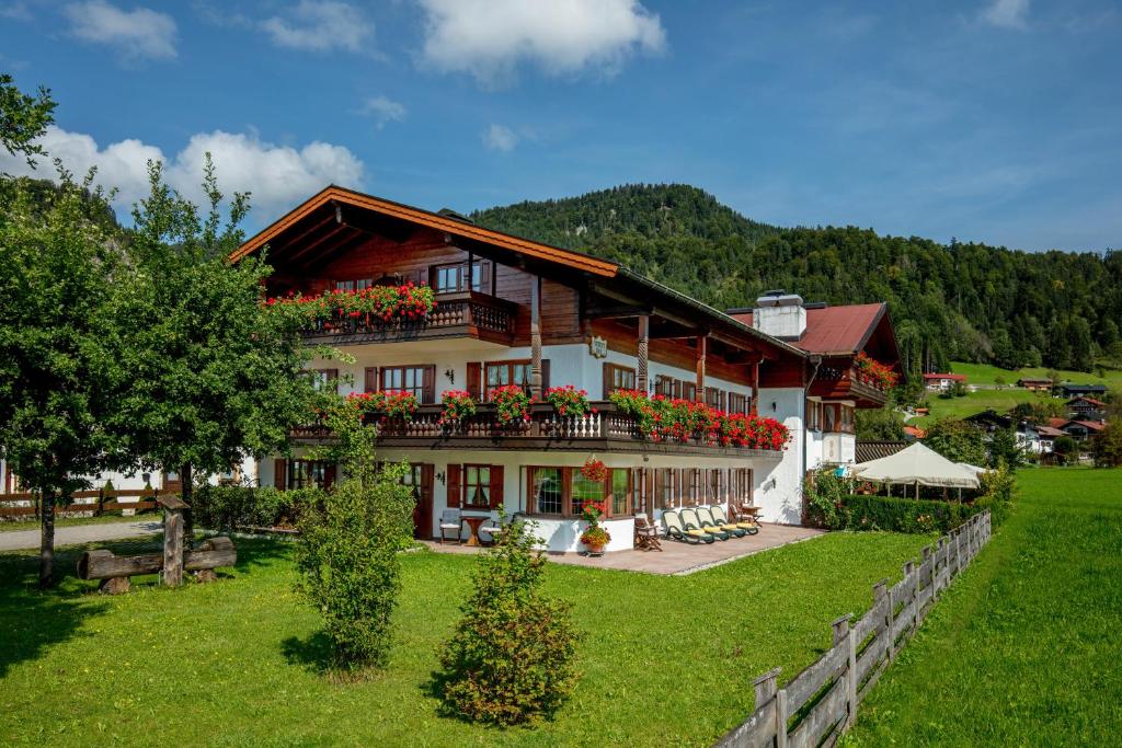 a large house with flowers on the balcony at Zum Eichhof Zimmer 12 in Reit im Winkl