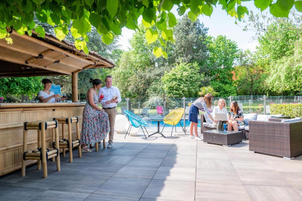 un groupe de personnes assises à un bar sur une terrasse dans l'établissement Novotel Lens Noyelles, à Noyelles-Godault
