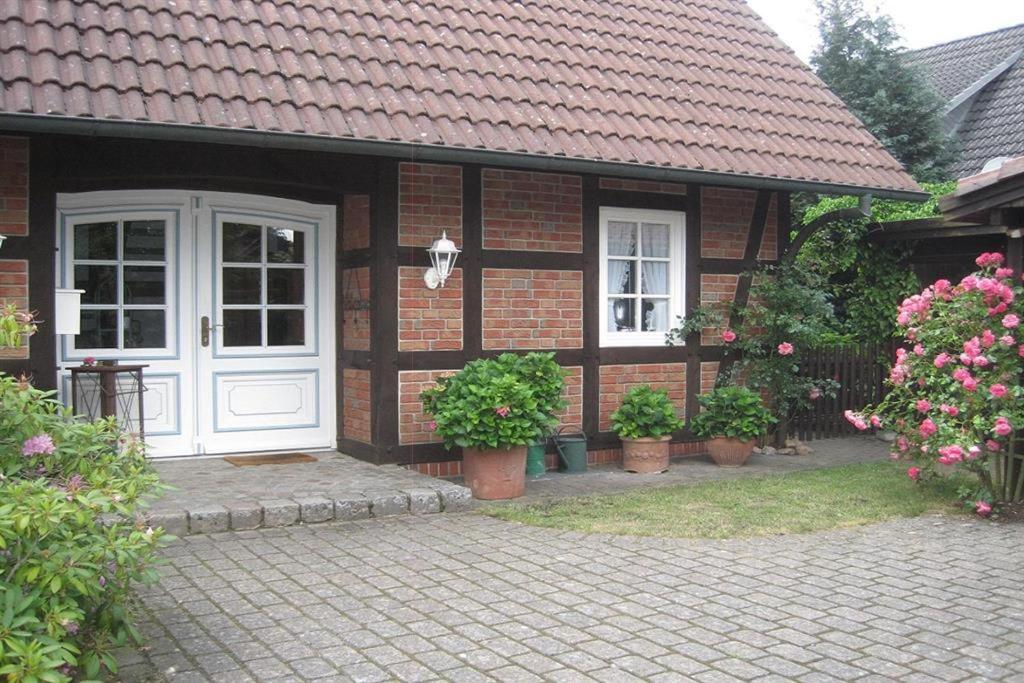 une maison en briques avec une porte blanche et des plantes en pot dans l'établissement 4-Jahreszeiten-Idylle Ollsen, à Hanstedt