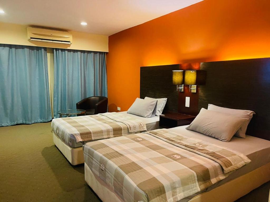 two beds in a hotel room with orange walls at MJ STUDIO ROOM in Kota Kinabalu