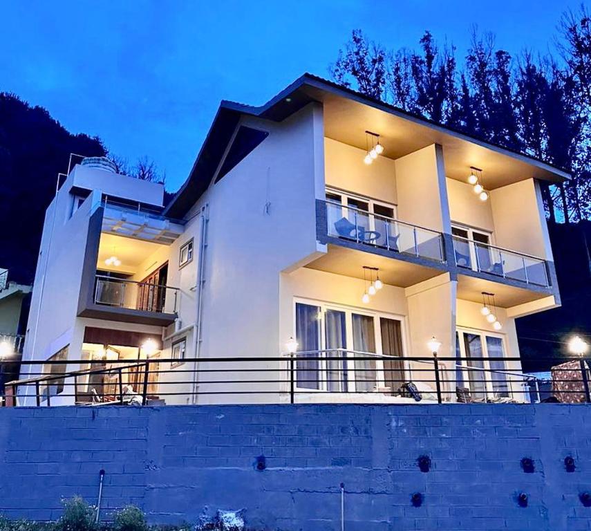 a large white house with a balcony at night at Ponmari Villa in Ooty